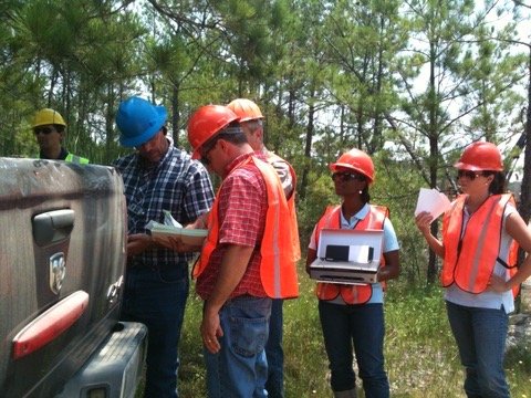 The team gathered at a truck tailgate in the forest, reviewing data on a field laptop