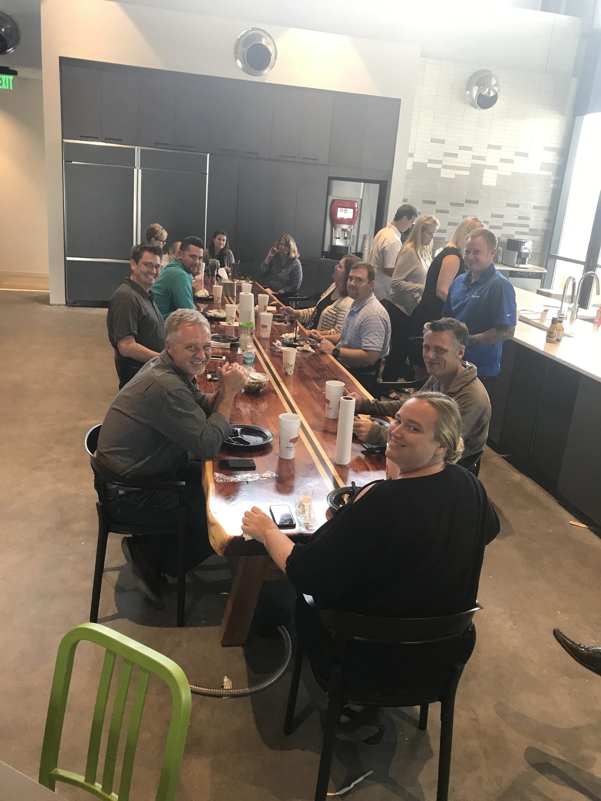 The team sharing a barbecue lunch along one long wooden table