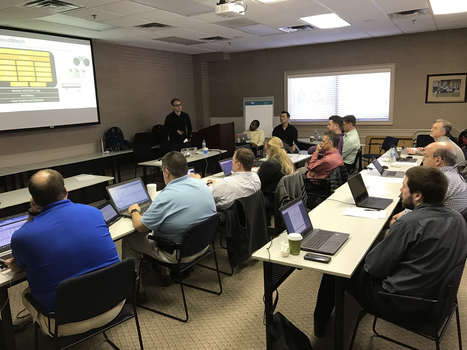 A classroom-style AWS training session with attendees following along on laptops
