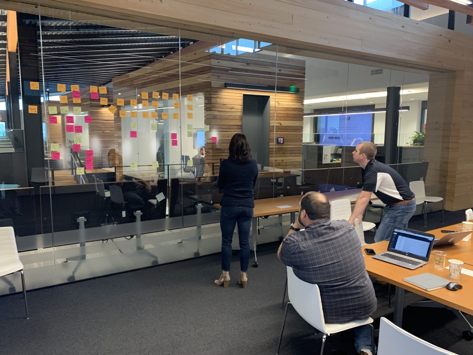 A facilitated working session: colleagues mapping a process with sticky notes across a glass wall